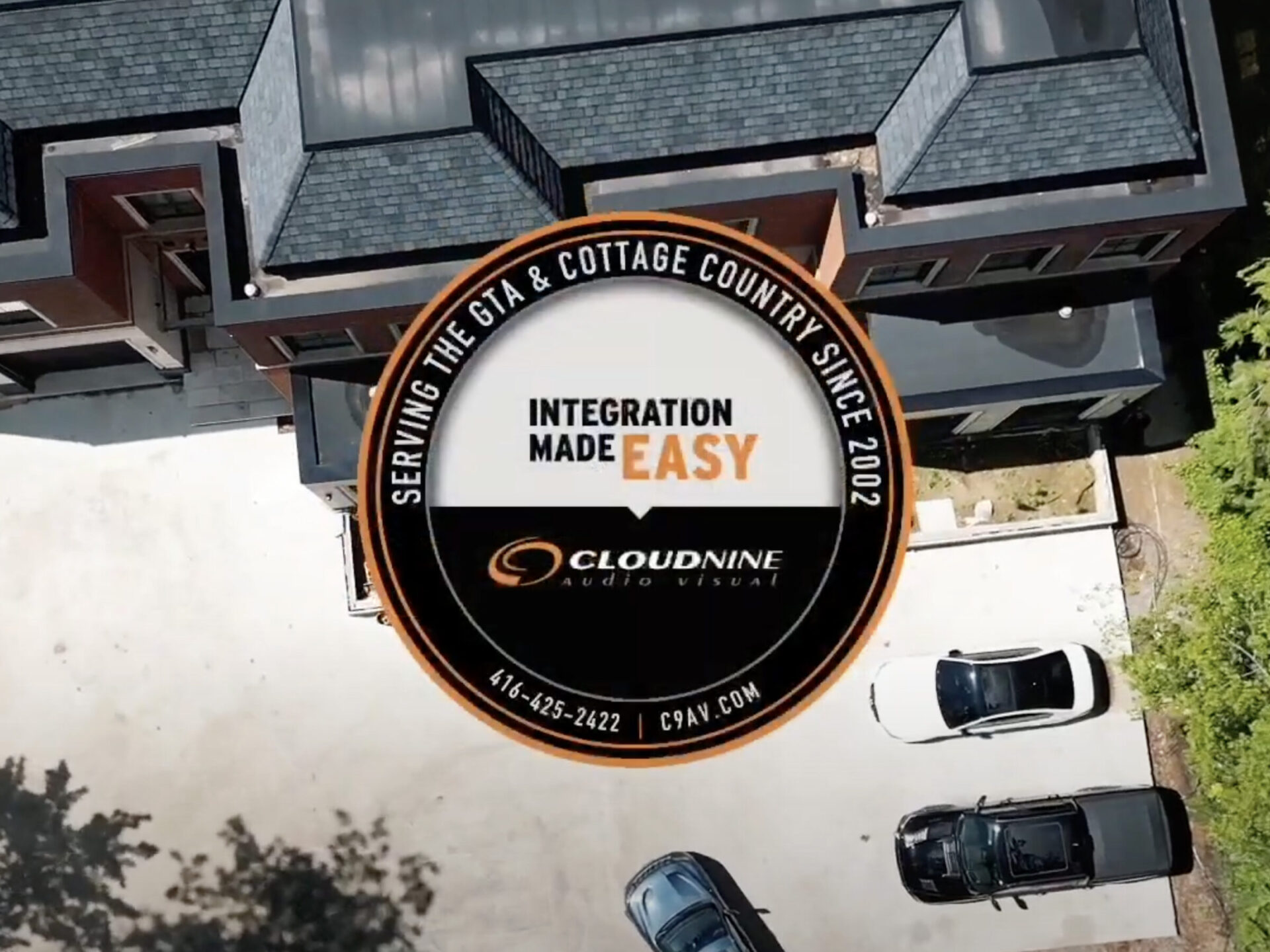 Aerial view of a modern building with parked cars. Large overlay promotes CloudNine Audio Visual services, showcasing "Integration Made Easy" slogan.