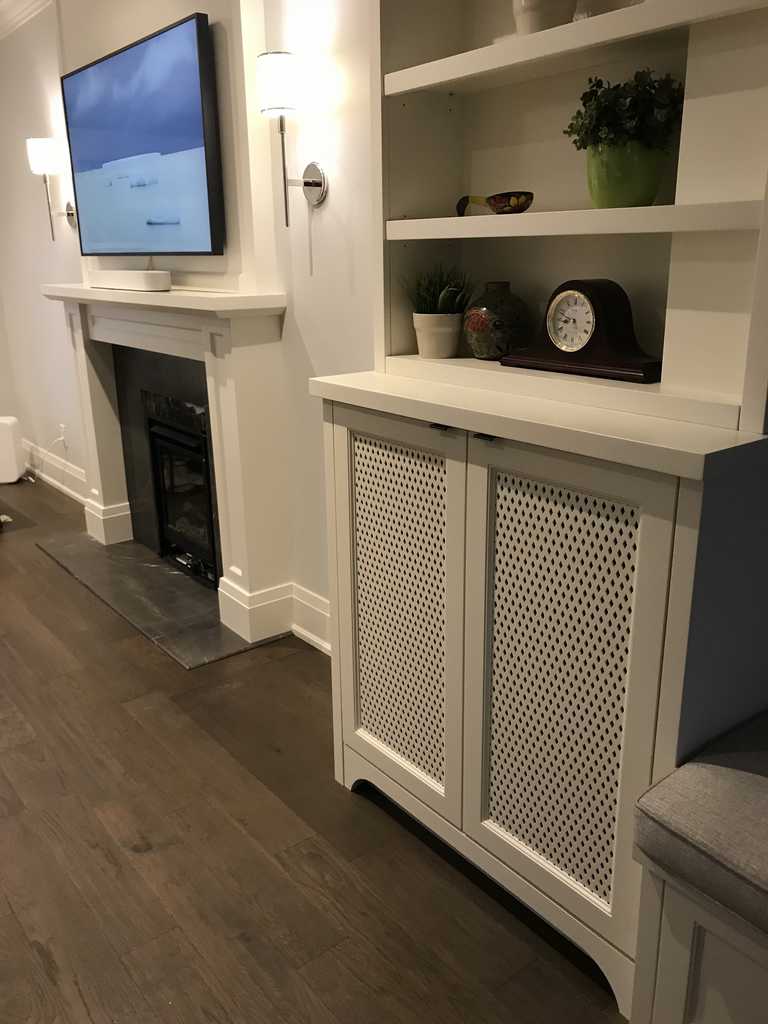 A cozy living room features a wall-mounted TV, fireplace, and white cabinetry with decor items, creating a warm and inviting atmosphere.