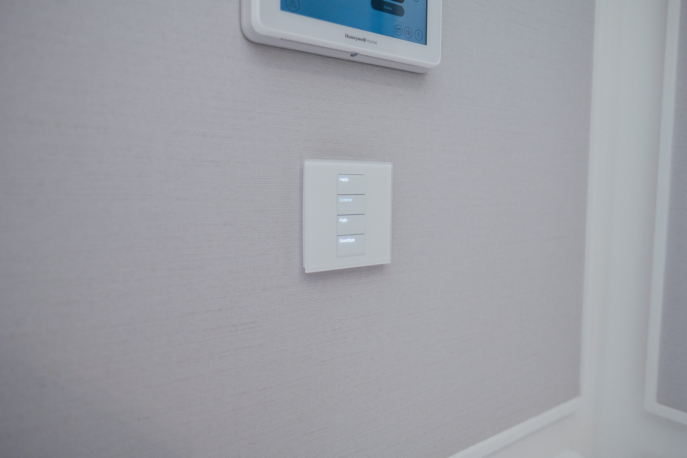 A minimalist interior wall with a digital control panel and touch-sensitive switches. The room has a modern, sleek design with light-colored walls.