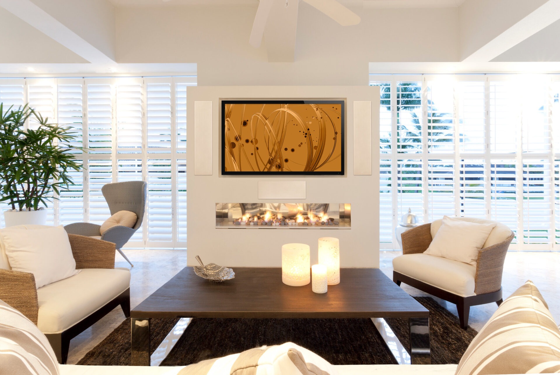 Modern living room features cozy seating, a fireplace, abstract art, candles, and large windows with shutters, creating a bright, tranquil atmosphere.