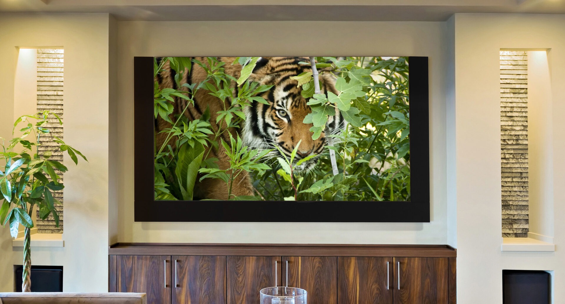 A luxurious living room features a large framed image of a tiger among greenery. Elegant lighting and wooden cabinetry enhance the sophisticated atmosphere.