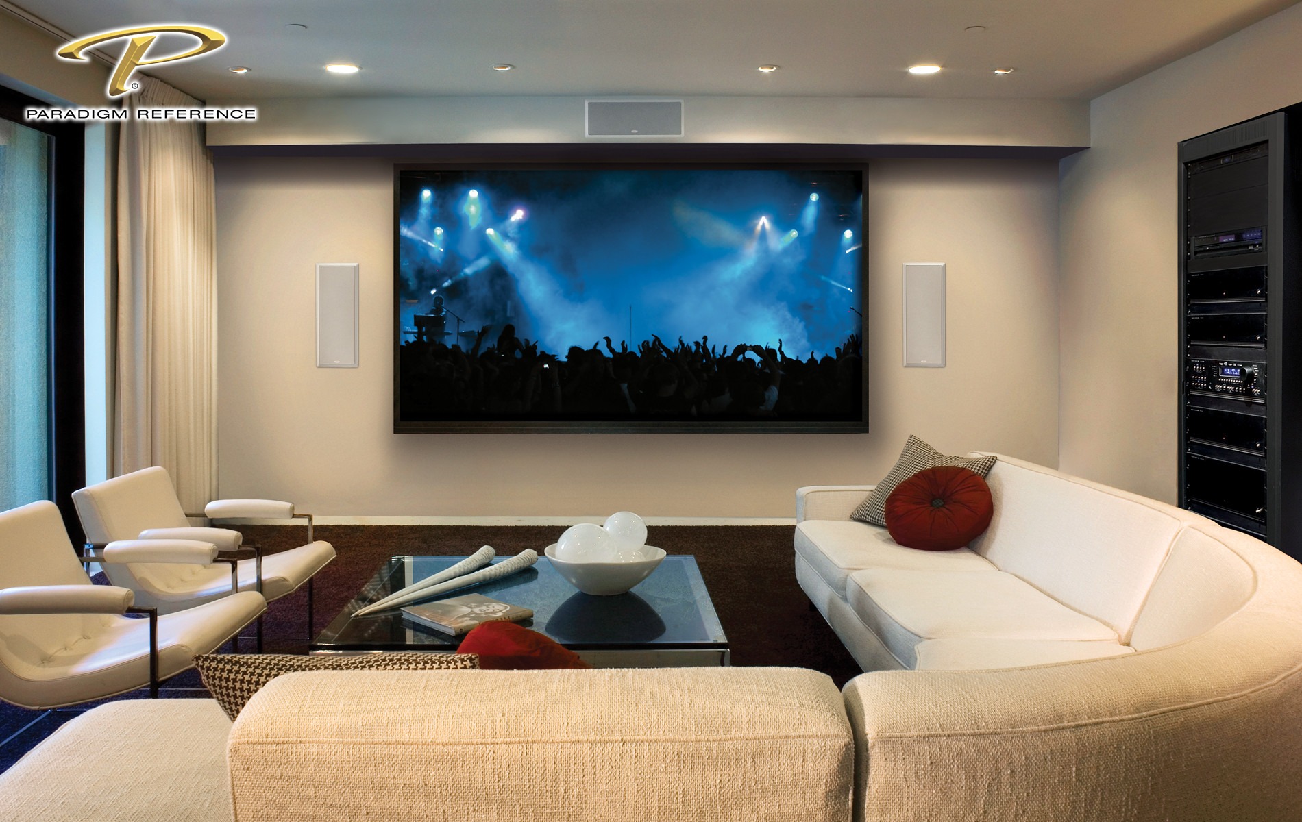 A modern home theater features a large screen showing a concert. Comfortable seating and a contemporary design create an inviting atmosphere.