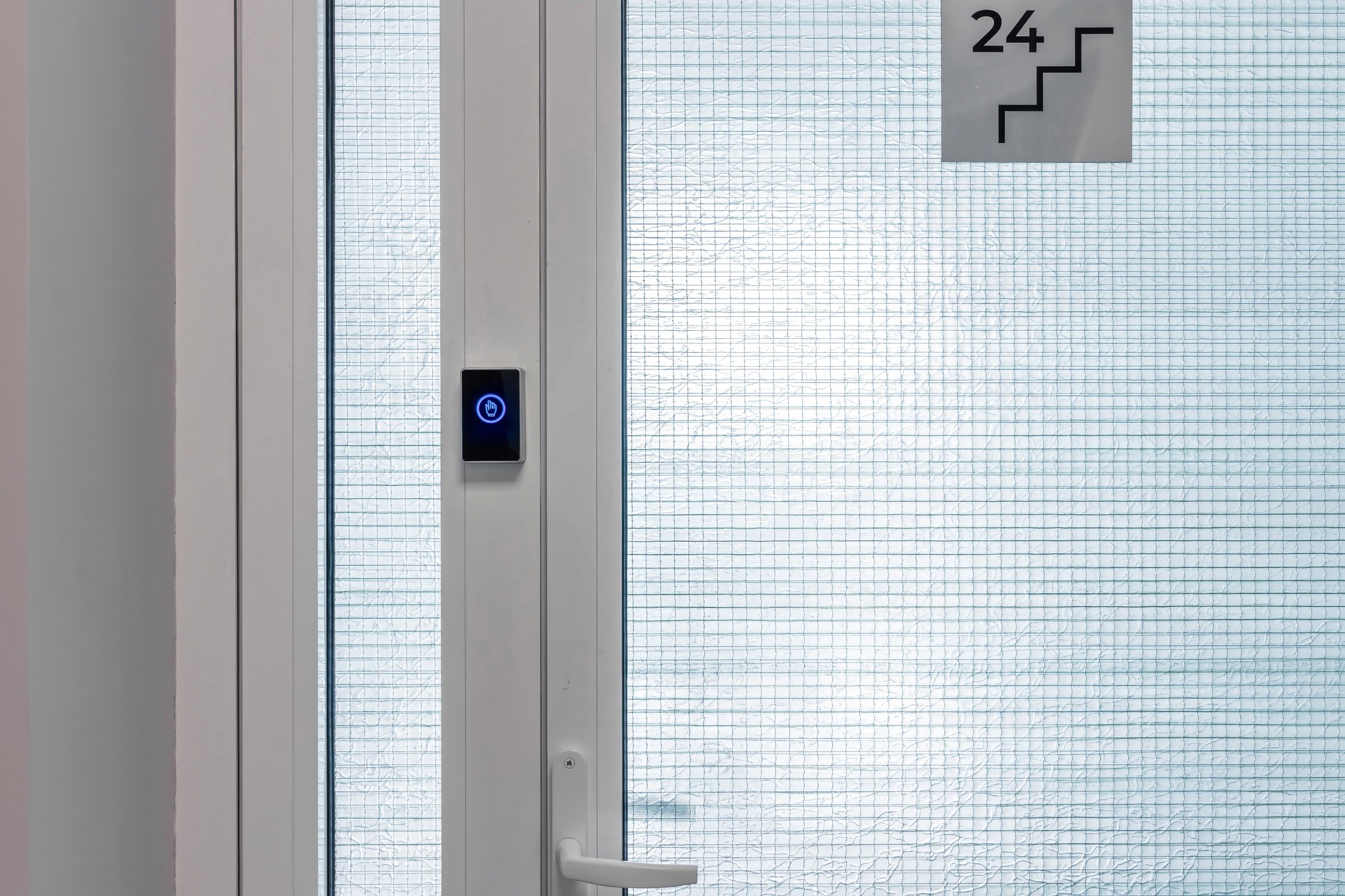 White door with a glass panel, electronic lock, and stairway sign marked "24." Minimalistic interior setting with natural light.