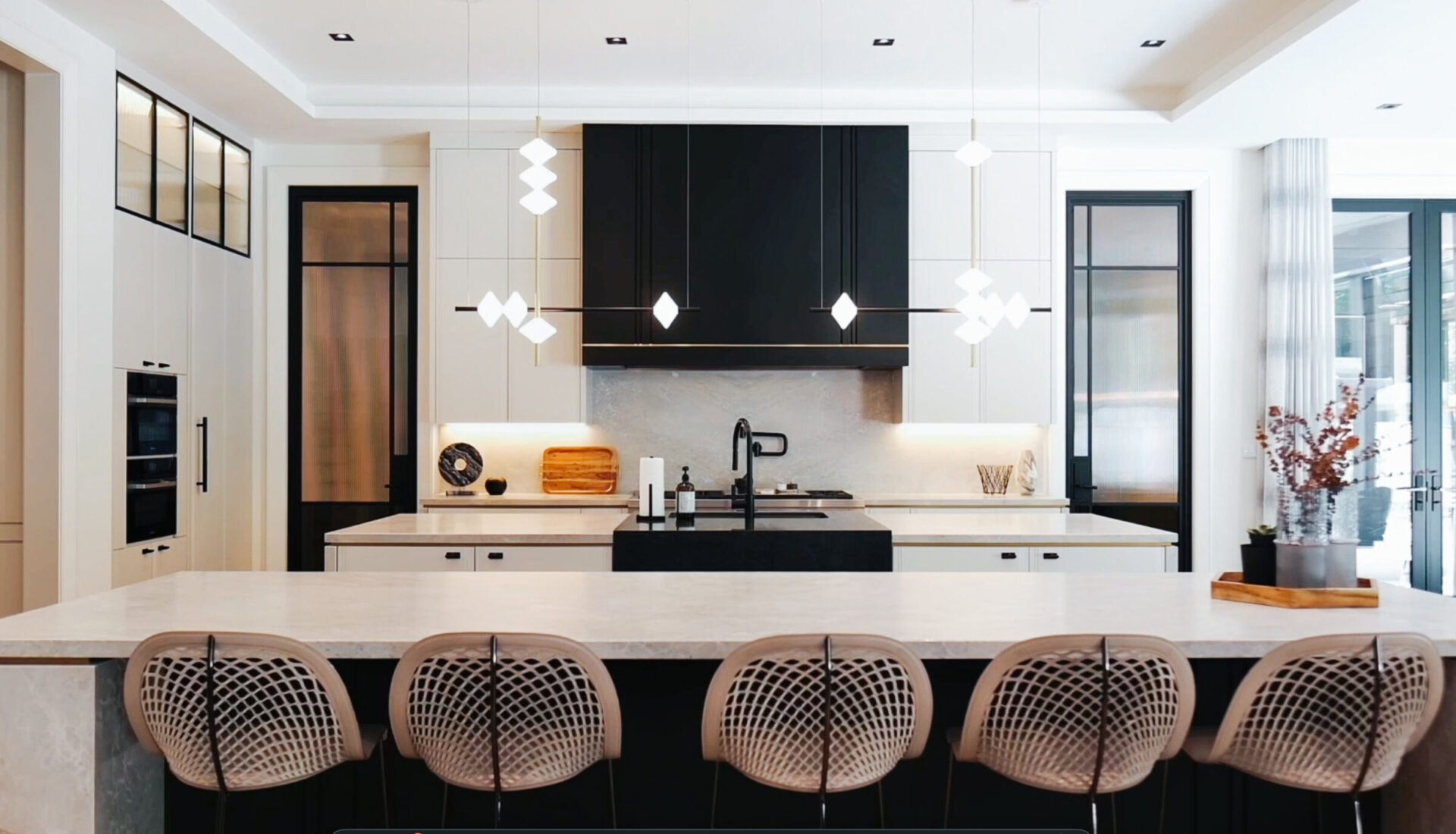 Modern kitchen with marble island and stylish pendant lights. Sleek black and white design, equipped with contemporary appliances and decorative elements. Bright and spacious.