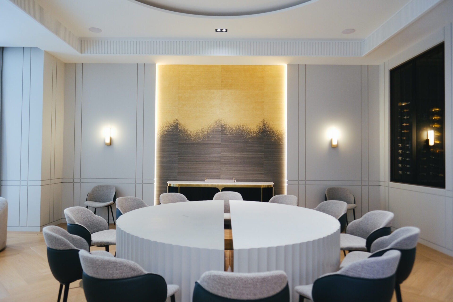 A modern conference room with a circular table and chairs, minimalistic design, and soft lighting highlighting the textured wall backdrop.