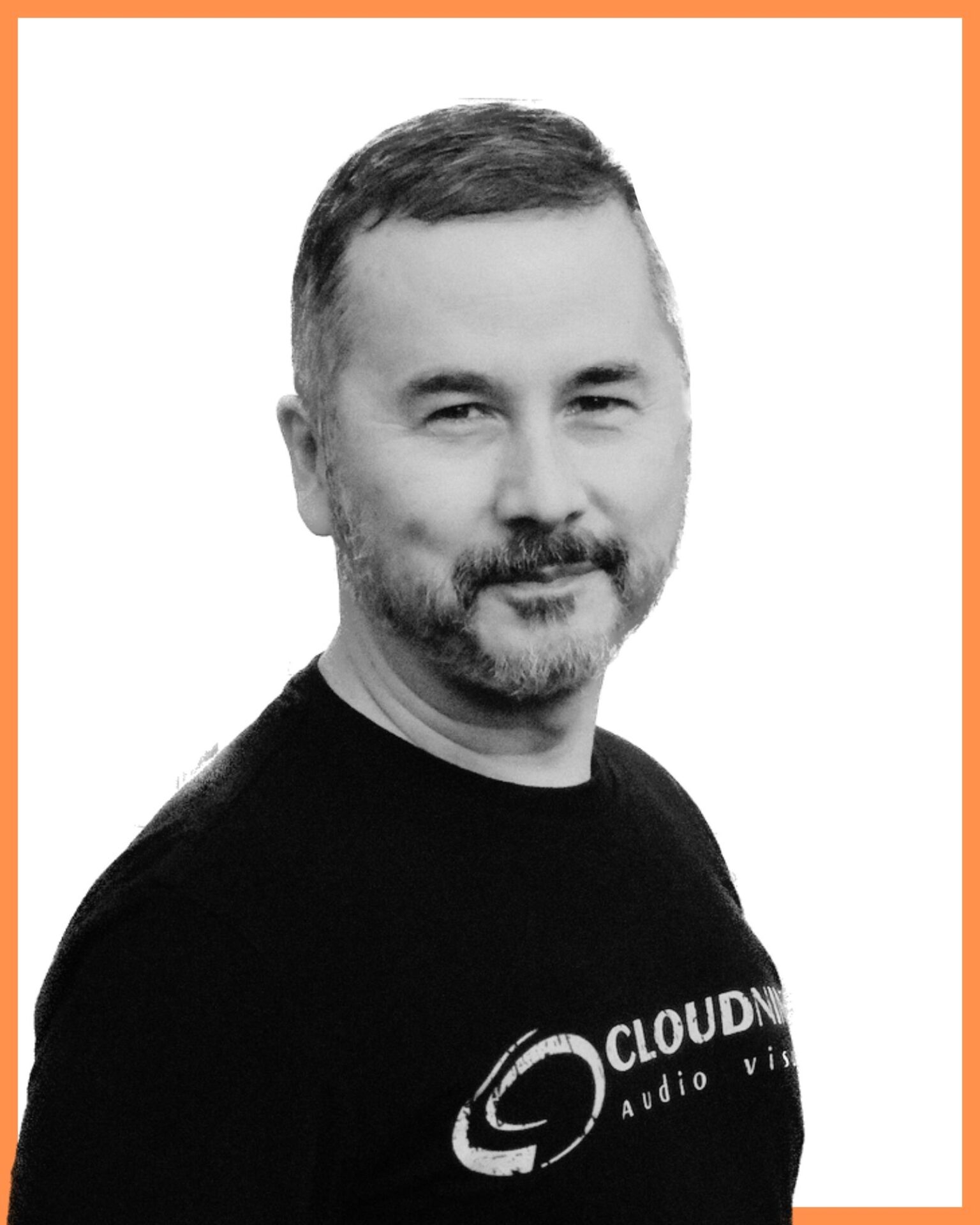 A person with short hair, beard, and a t-shirt that reads "Cloudness Audio Visual," is in a simple, bordered portrait with an orange frame.