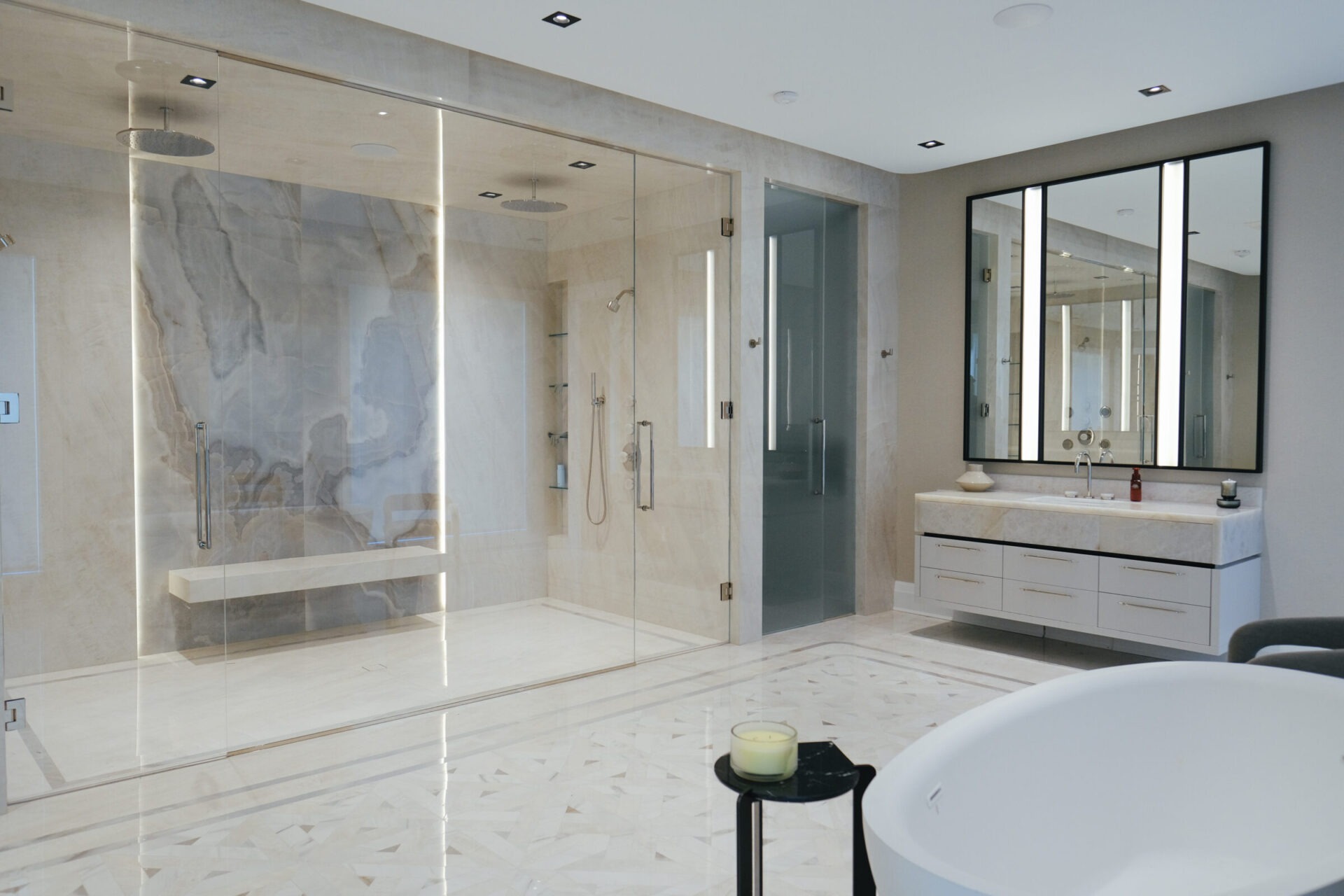 Luxurious bathroom with large glass shower, elegant marble walls, double vanity, illuminated mirror, and modern bathtub. Minimalistic design with soft lighting and stylish fixtures.