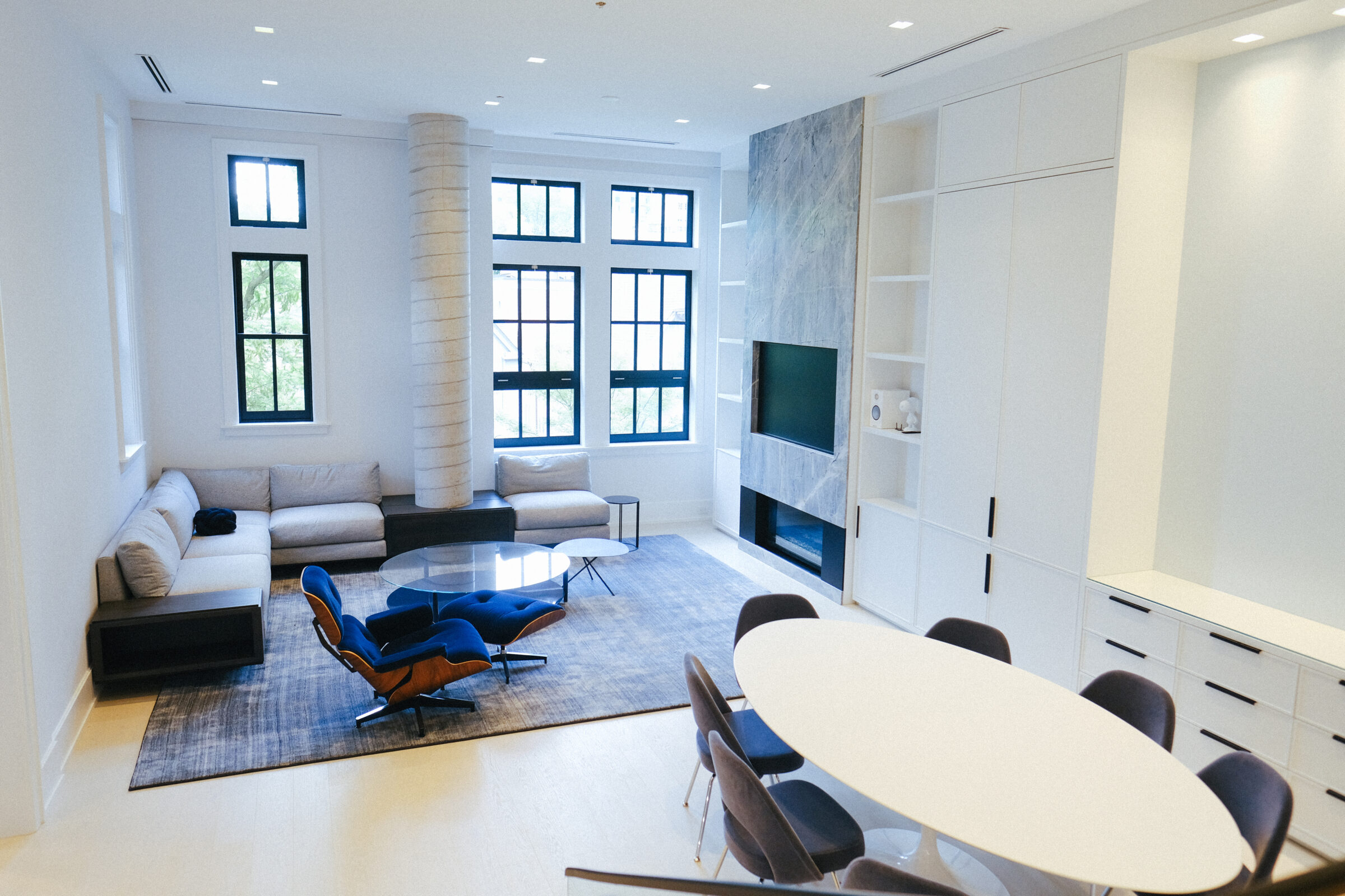 A modern living room with large windows, cozy seating, a round dining table, and a minimalist design featuring bright, natural lighting.