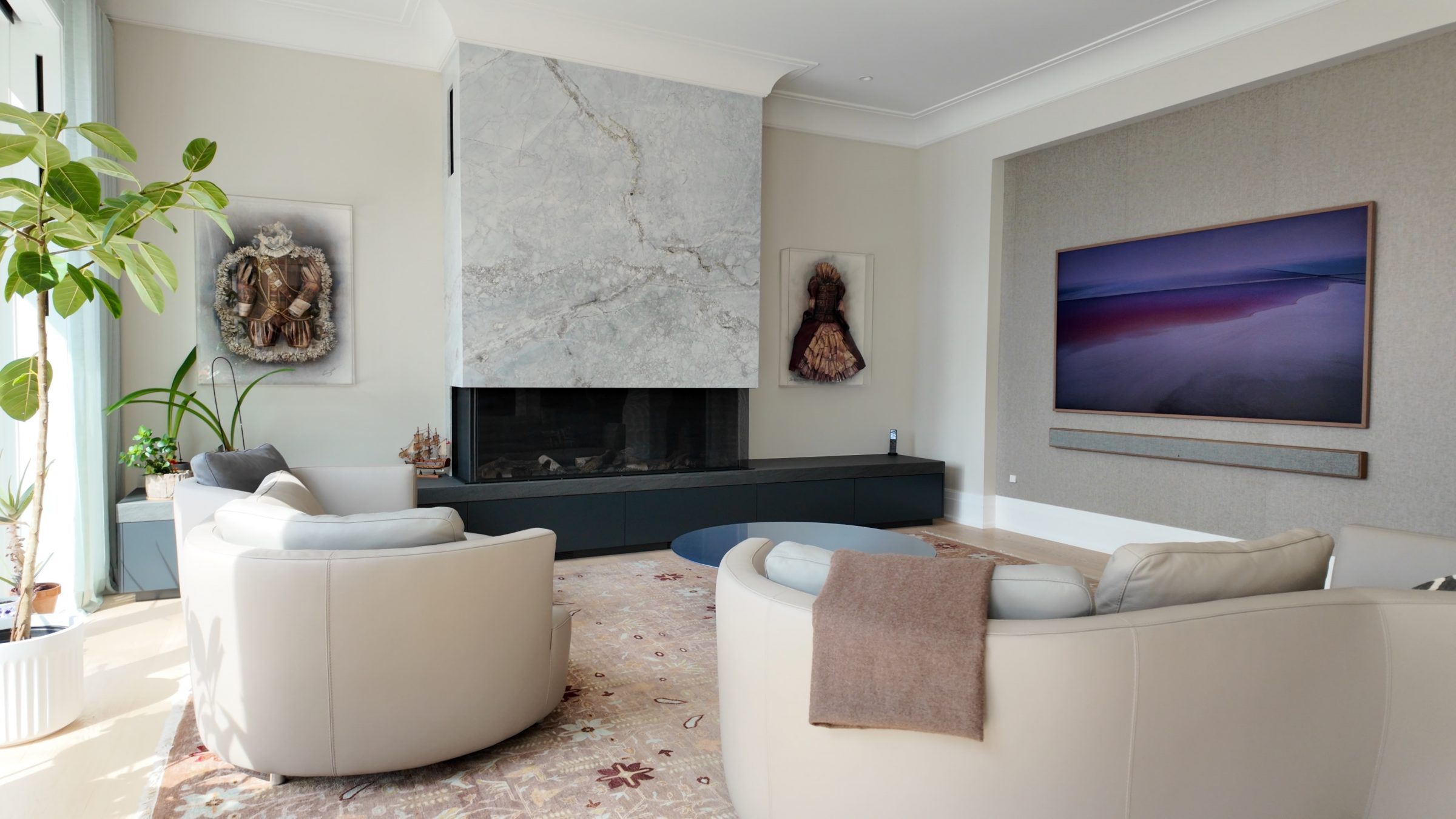 Modern living room with a large sectional sofa, elegant shelving, abstract lighting fixtures, and a mounted TV on a marble accent wall. Cozy and stylish ambiance.